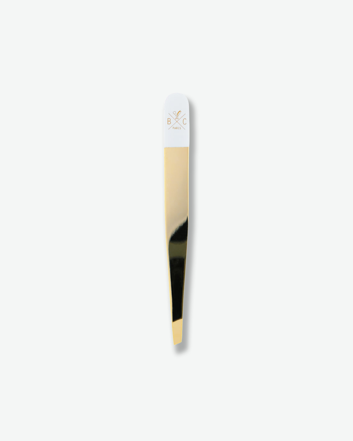 Luxury gold and white slanted tweezers isolated on a plain white background.