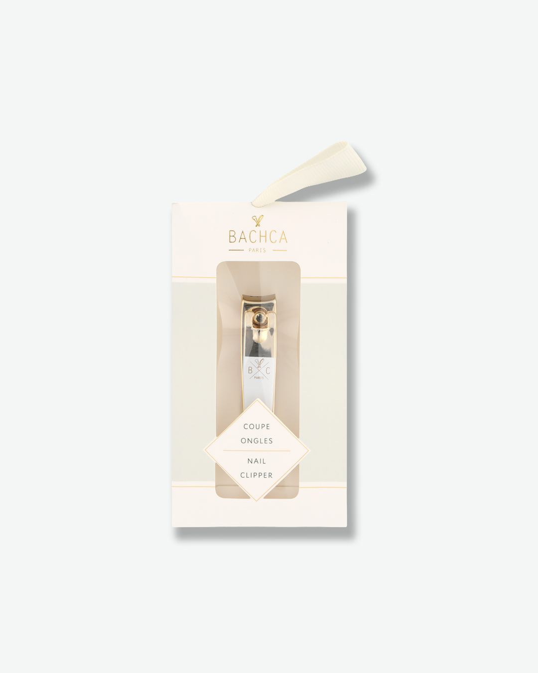 Luxury gold and white nail clipper in its elegant cream-colored retail packaging on a white background.