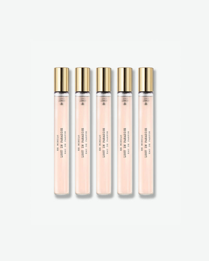 A set of five identical Ex Nihilo Lust in Paradise Eau de Parfum travel spray vials showing a light pink liquid formula inside clear glass tubes with gold caps, isolated on a light grey background.