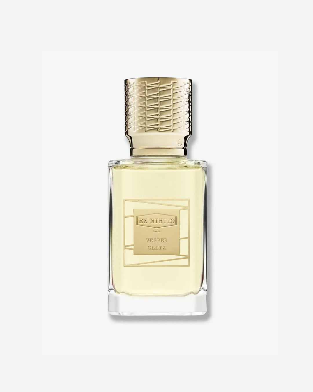 Ex Nihilo Vesper Glitz Eau de Parfum in a heavy clear glass bottle showcasing a pale yellow liquid, topped with an intricately engraved gold cap and a matching gold geometric label, isolated on a light grey background.