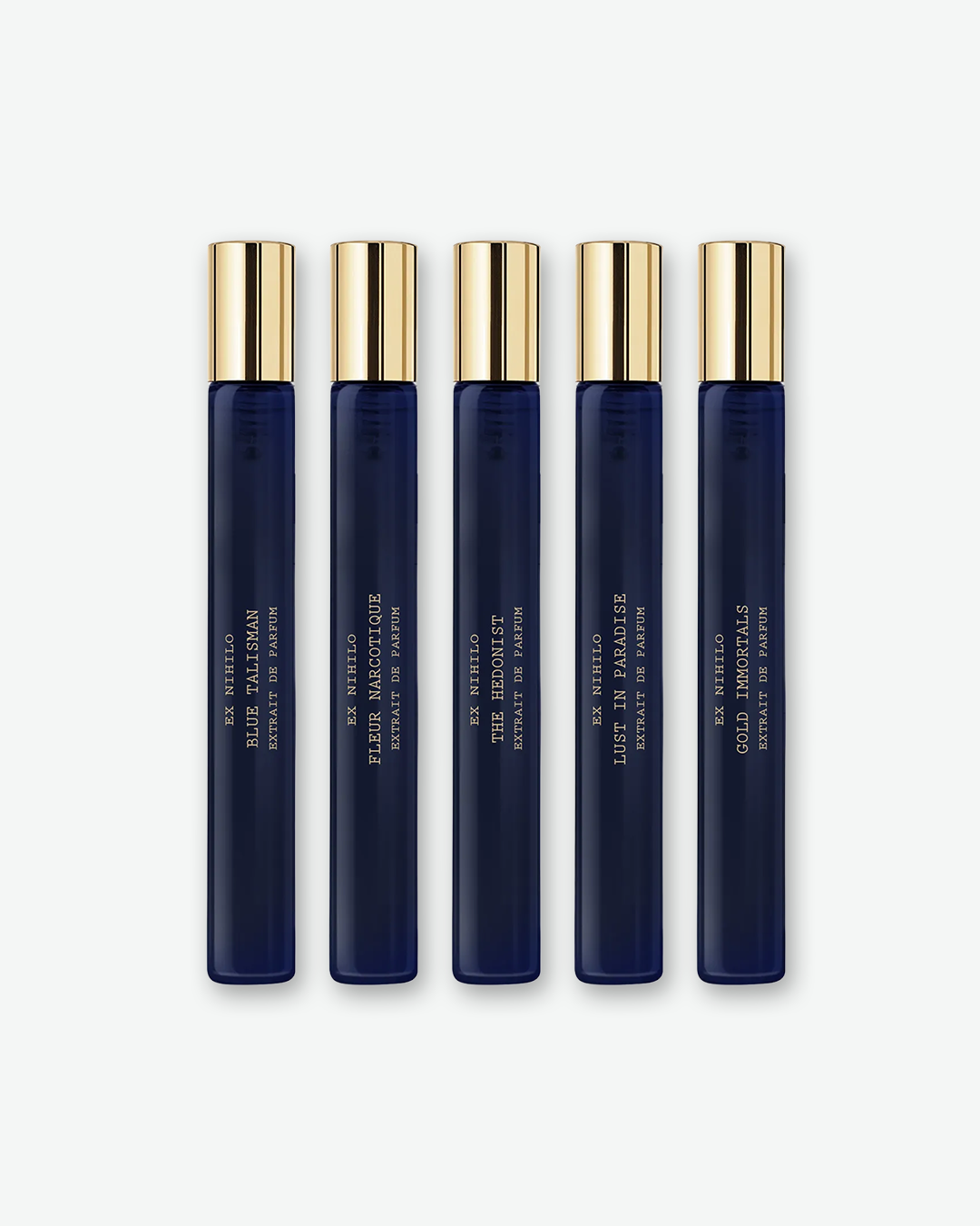 Five slender, dark blue glass perfume travel vials lined up vertically side-by-side against a plain off-white background. Each vial features a polished gold cap and gold lettering detailing the brand "EX NIHILO" and individual scent names from left to right: Blue Talisman, Fleur Narcotique, The Hedonist, Lust in Paradise, and Gold Immortals.