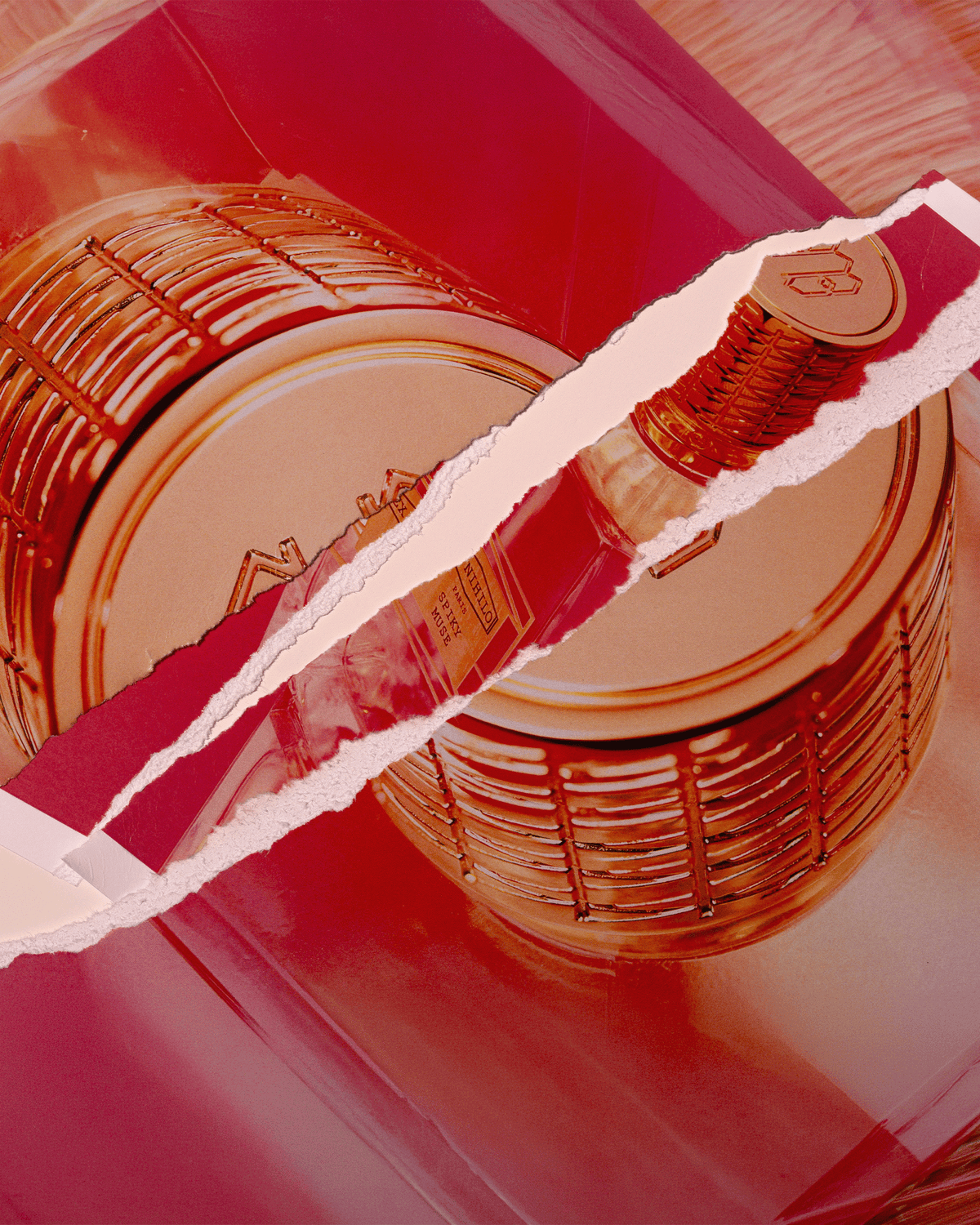 A close-up of a cylindrical bottle with a ribbed metallic cap, shown through a torn-paper overlay on a glossy red background.