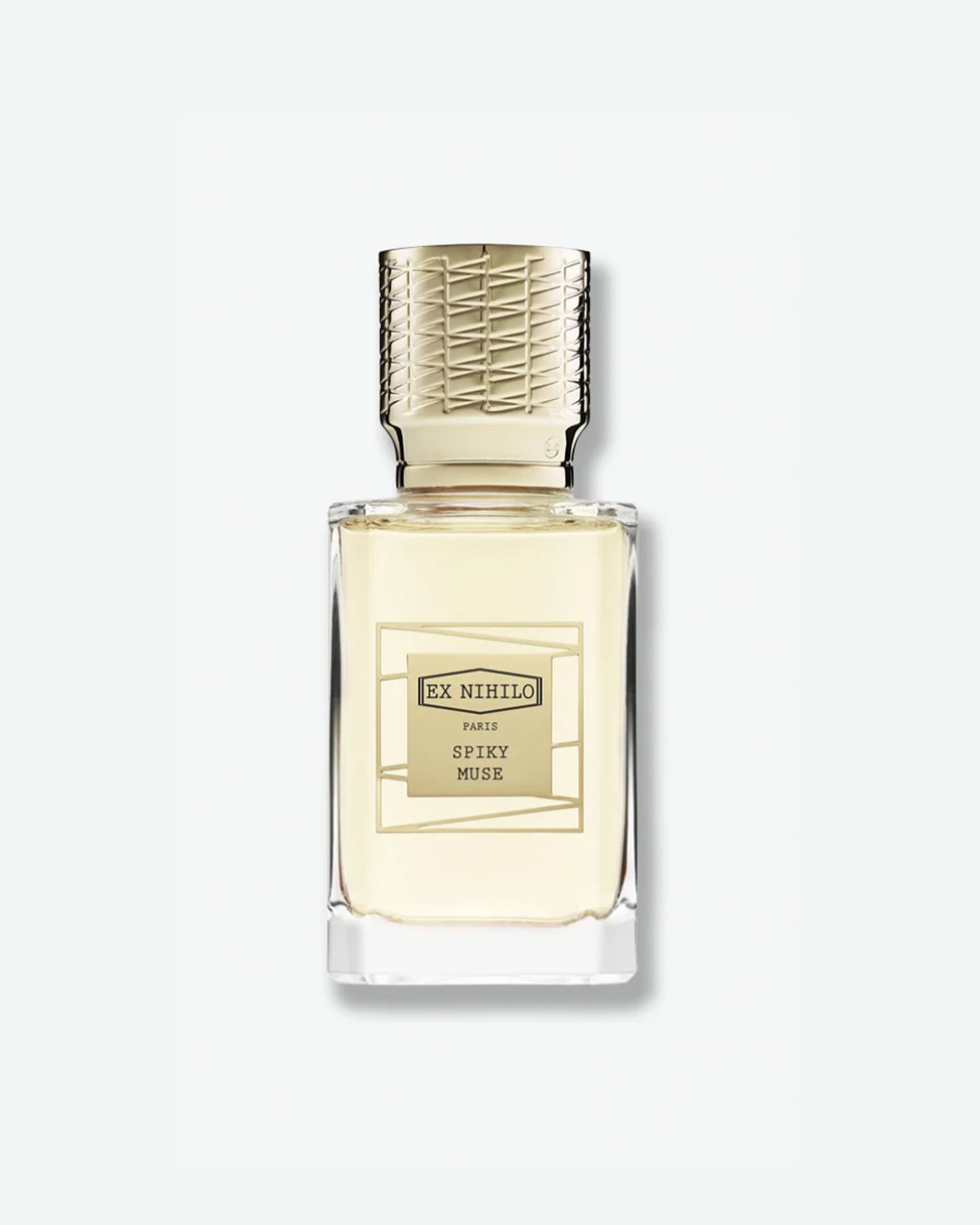 Ex Nihilo Spiky Muse Eau de Parfum in a heavy clear glass bottle showcasing a pale yellow liquid, topped with an intricately engraved gold cap and a matching gold geometric label, isolated on a light grey background.