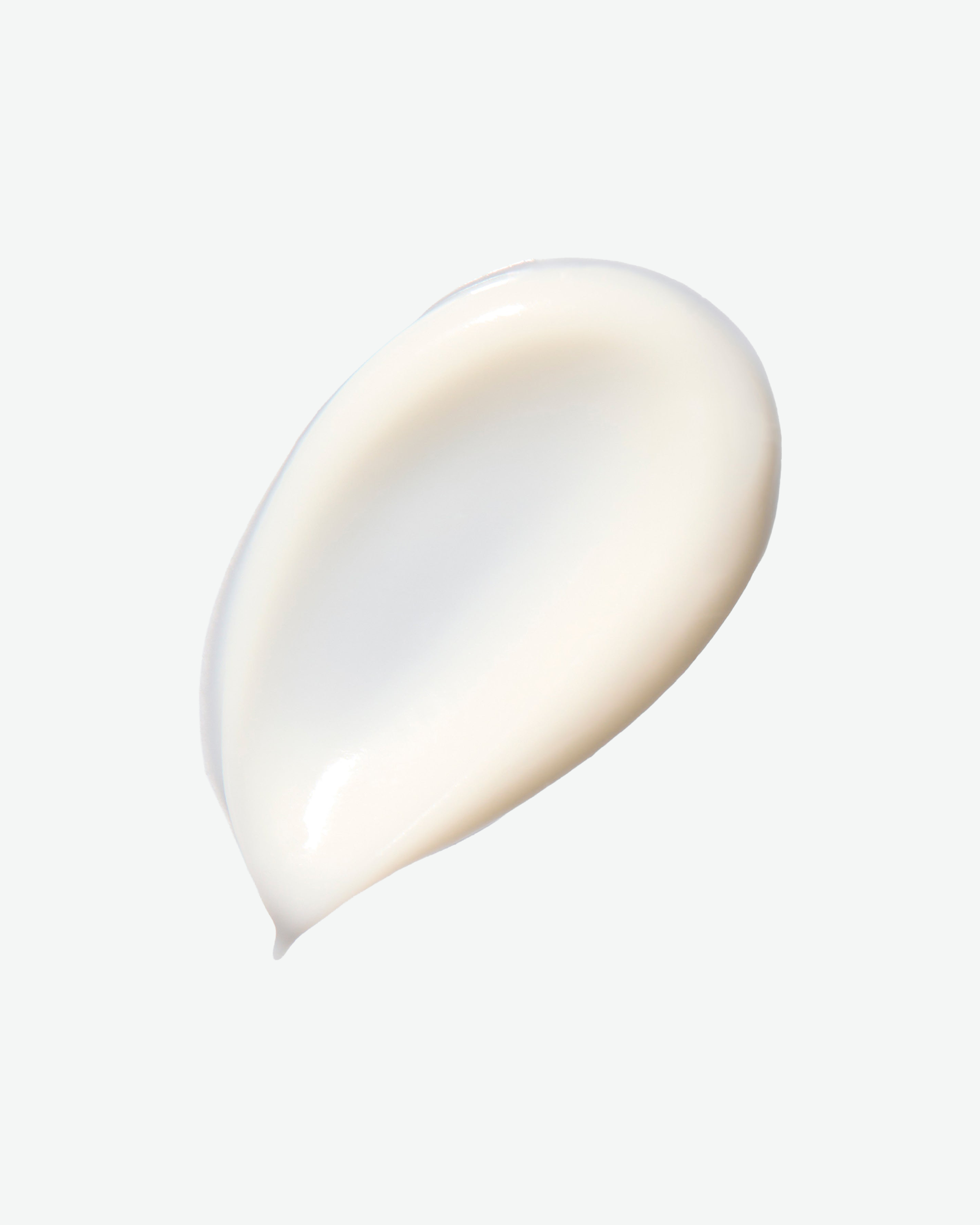 A smooth, glossy smear of creamy off-white cosmetic product on a clean, light gray background.