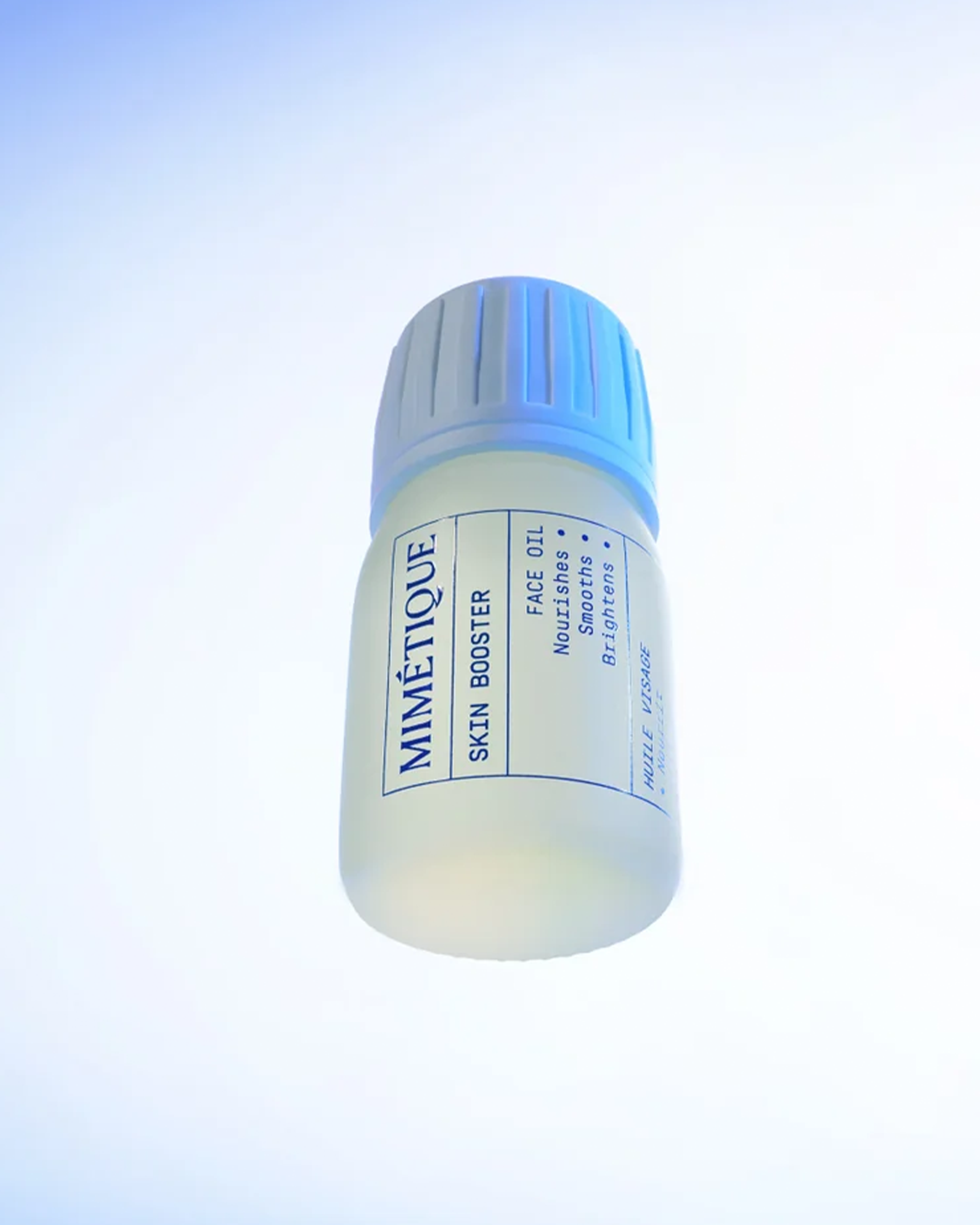A small cylindrical bottle of Mimètique Skin Booster face oil, featuring a translucent white body and a ribbed light blue cap, centered against a bright white background.