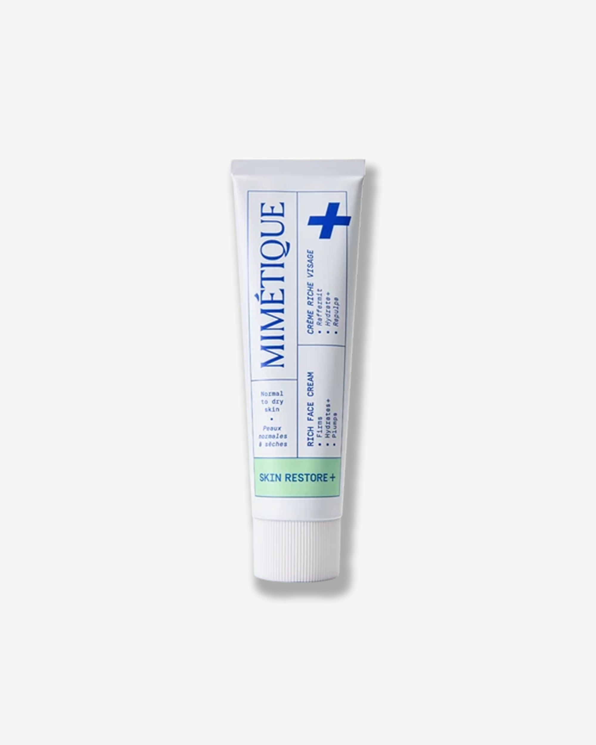 A white squeeze tube of Mimétique Skin Restore + Face Cream with blue and green text and graphics, centered on a light gray background.