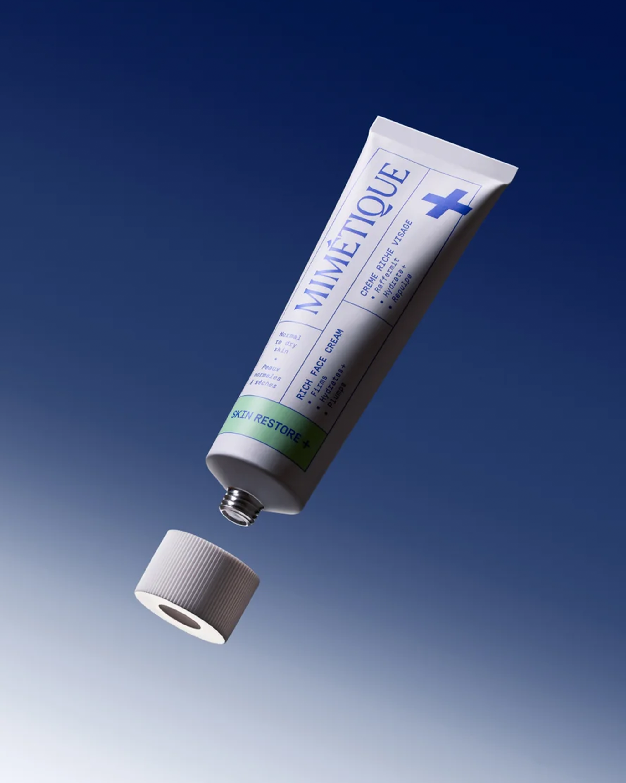 A tube of Mimètique ointment floating above its cap against a blue gradient background. The tube is white with blue text and a blue cross, and the cap is a ribbed white plastic piece.