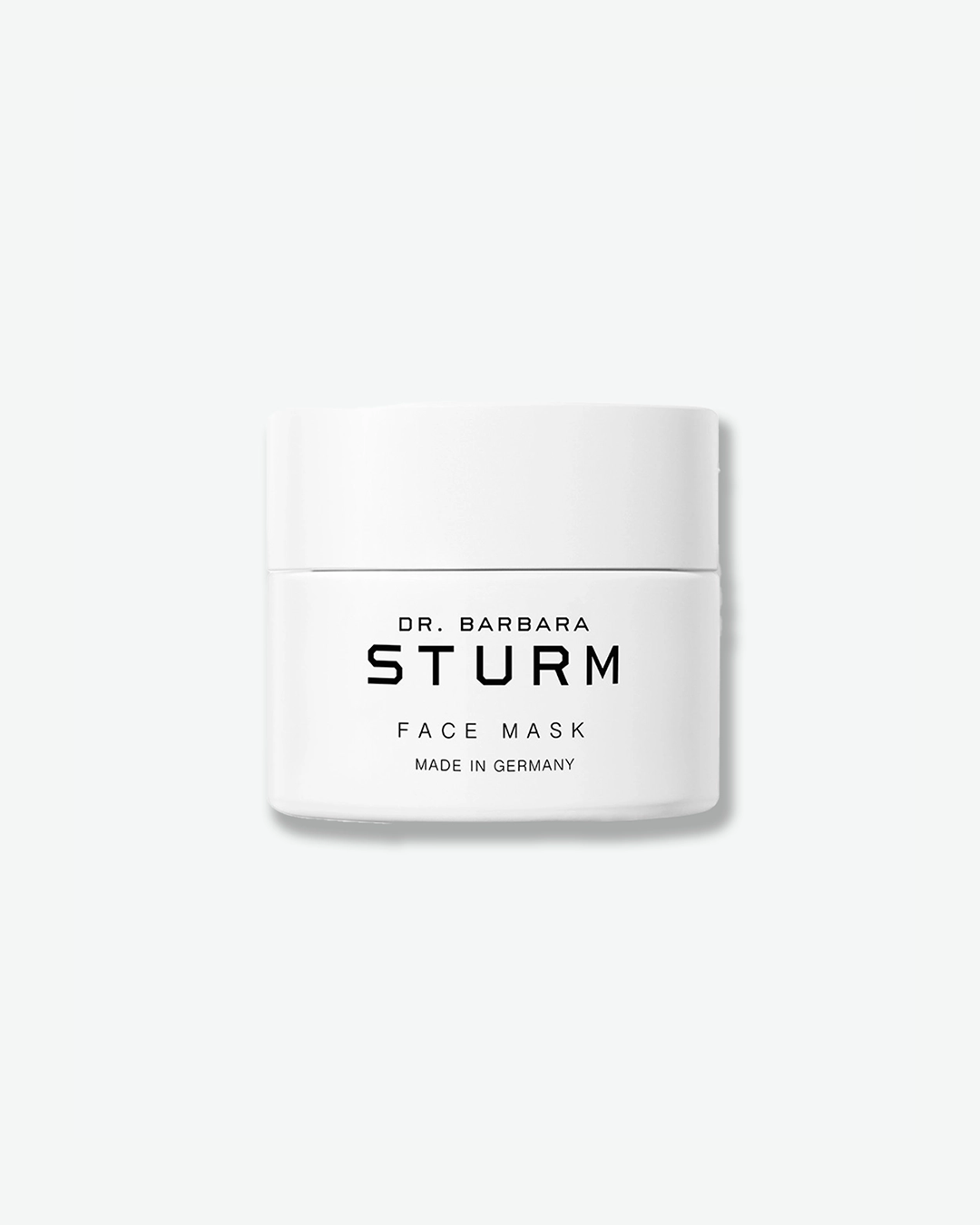 A product shot of a Dr. Barbara Sturm Face Mask jar, centered against a light gray background. The low white cylindrical jar is sealed with a matching flat white cap. The front displays clean black text reading "DR. BARBARA STURM", "FACE MASK", and "MADE IN GERMANY".