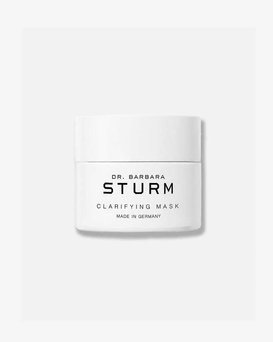 A product shot of a Dr. Barbara Sturm Clarifying Mask jar, centered against a plain light gray background. The short, cylindrical jar is solid white with a matching flat white screw cap. The front displays minimalist black text reading "DR. BARBARA STURM", "CLARIFYING MASK", and "MADE IN GERMANY".