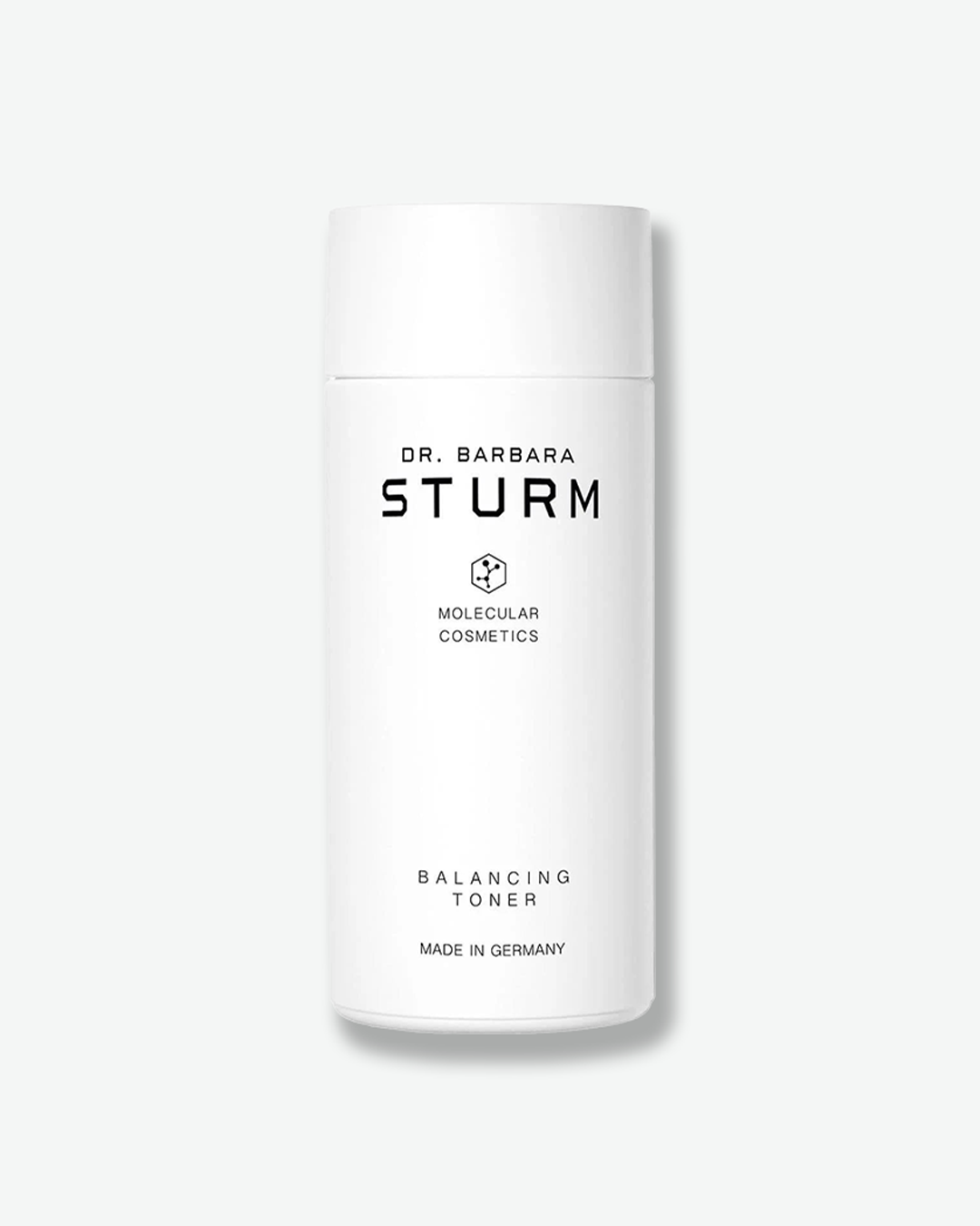 A product shot of a Dr. Barbara Sturm Balancing Toner bottle, centered against a plain light gray background. The cylindrical bottle is solid white with a matching flat white cap. The front displays minimalist black text reading "DR. BARBARA STURM", the molecular hexagon logo, "BALANCING TONER", and "MADE IN GERMANY".