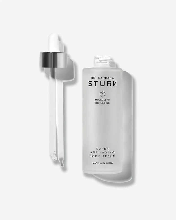 An open frosted glass bottle of Dr. Barbara Sturm Super Anti-Aging Body Serum, shown with the long glass pipette dropper resting alongside it.