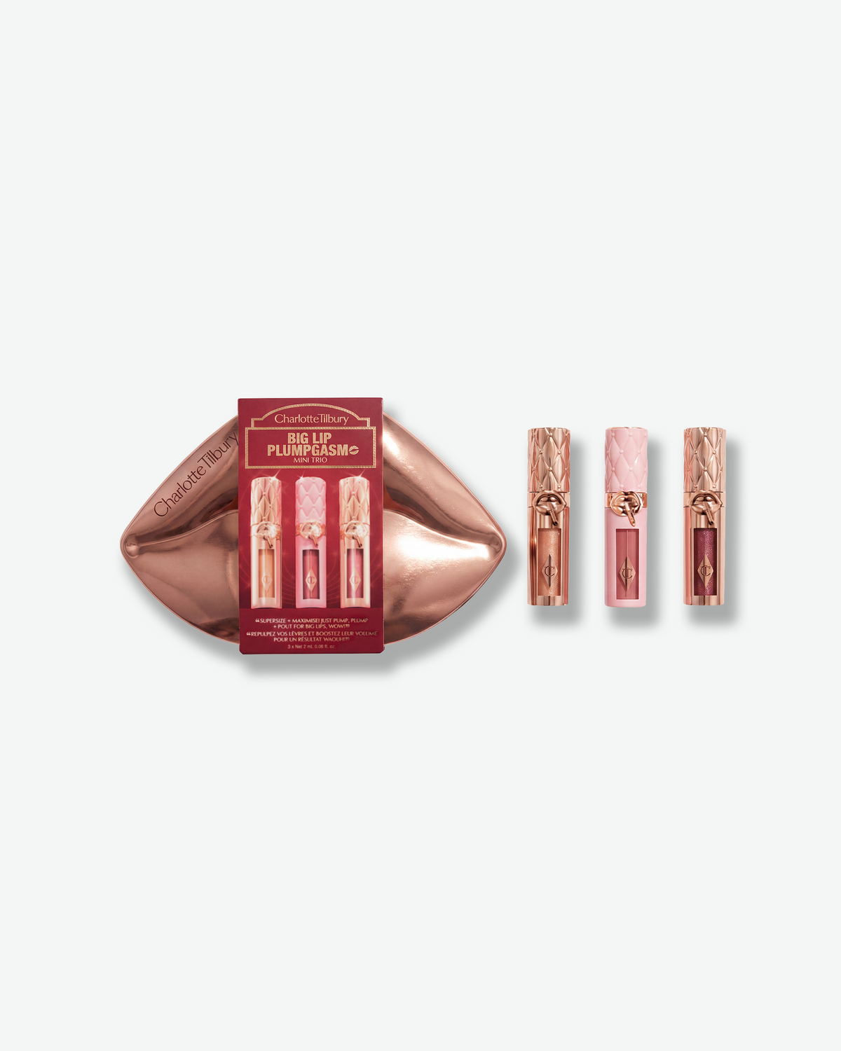 Charlotte Tilbury Big Lip Plumpgasm Mini Trio with three lip plumpers in rose-toned packaging, displayed with a metallic lip-shaped case.