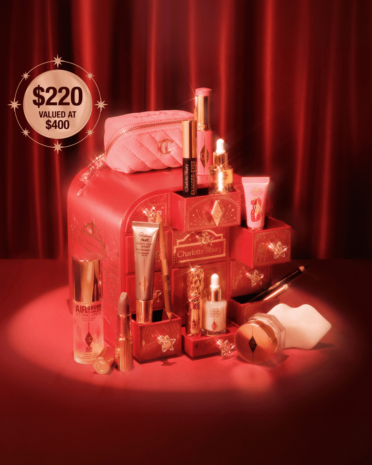 Charlotte Tilbury holiday beauty collection and advent calendar displayed together, featuring makeup, skincare, setting spray, lip products, mascara, serum, and a pink quilted makeup bag.