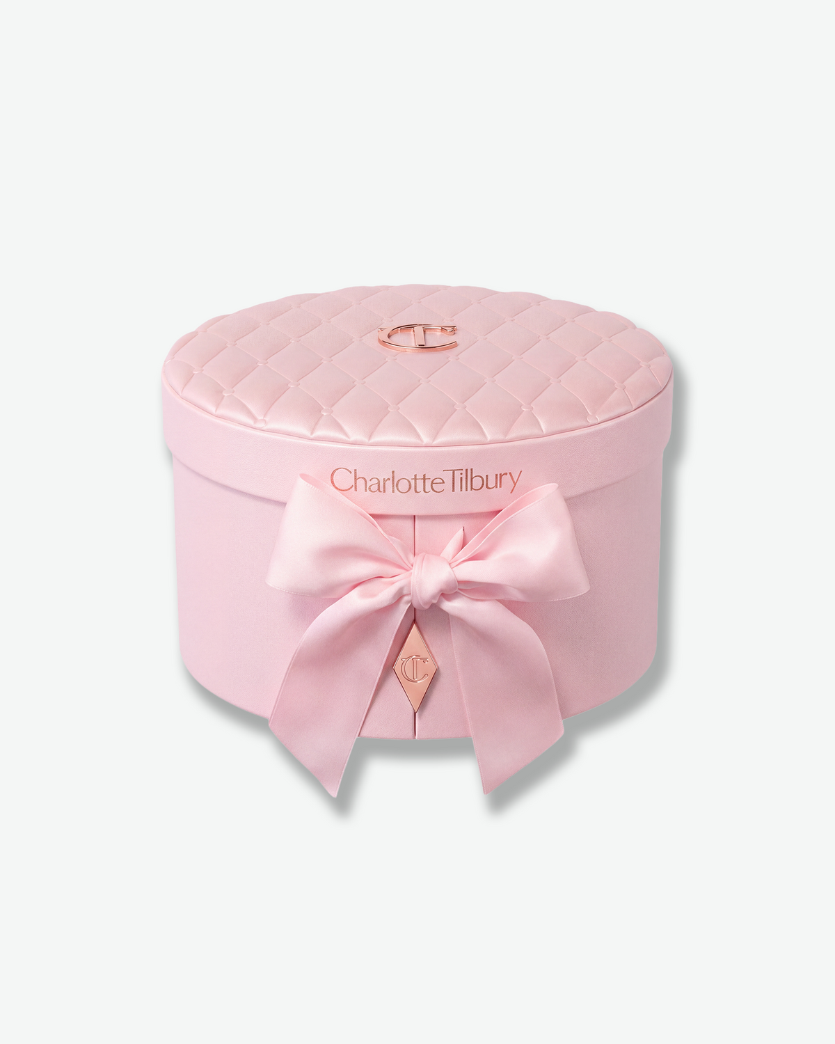 Pink Charlotte Tilbury quilted vanity case with satin bow and rose-gold CT logo.