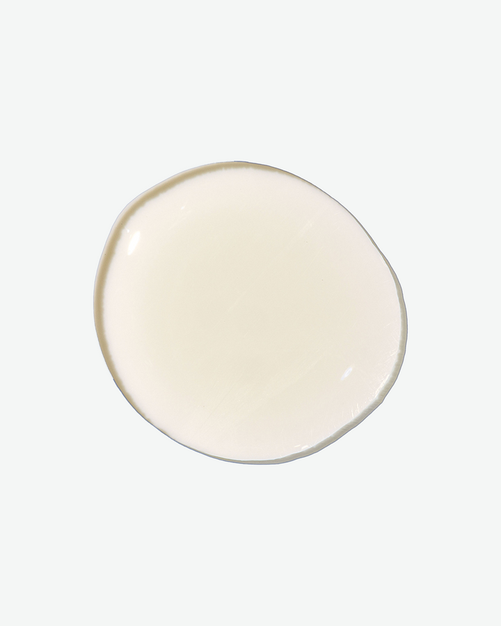 A top-down close-up shot of a single, clean droplet of transparent, pale liquid centered on a white background.