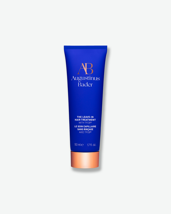 A bright blue squeeze tube of Augustinus Bader The Leave-In Hair Treatment with a metallic copper cap, centered on a light gray background.