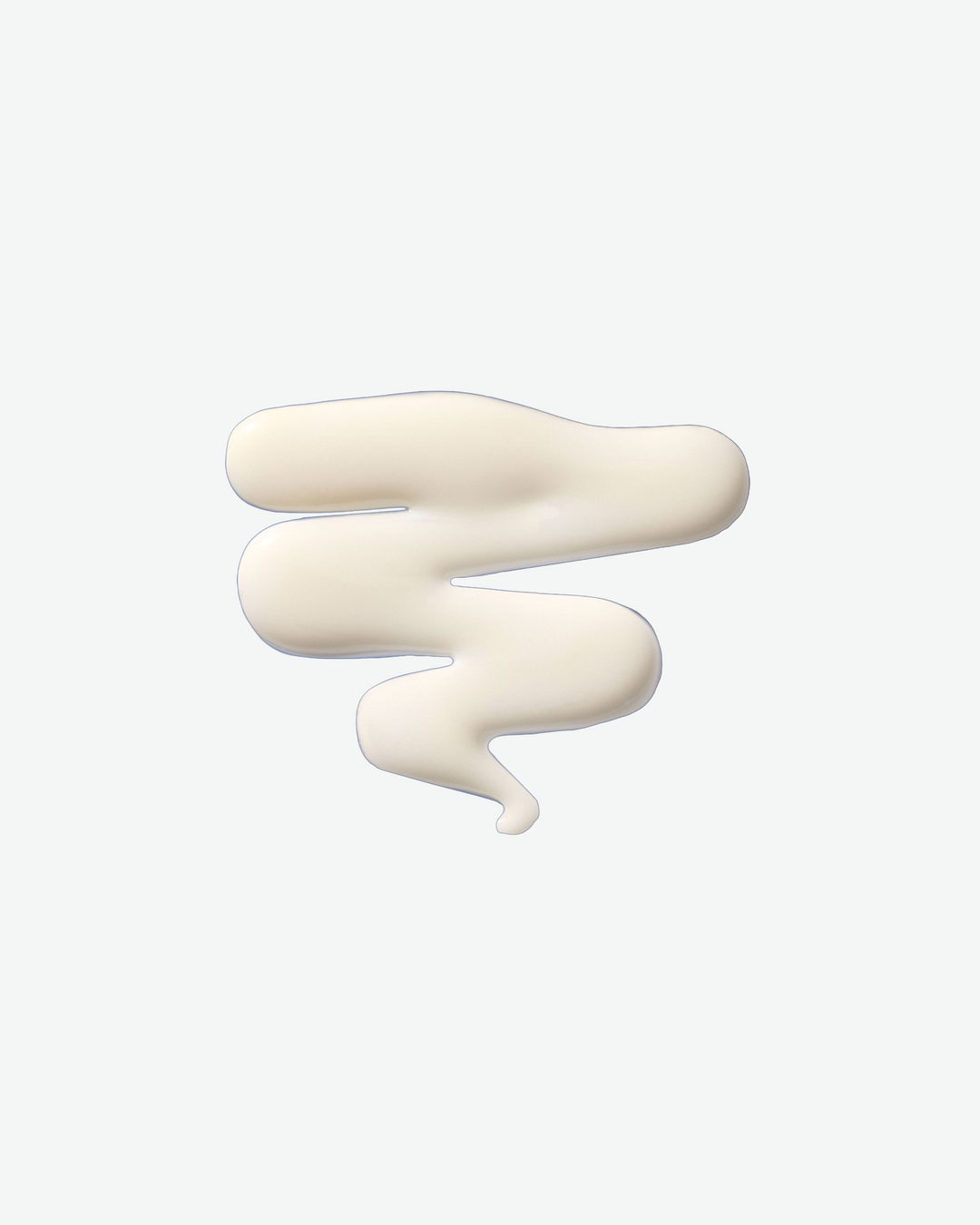A top-down close-up view of a thick, zigzag swatch of creamy white hair treatment lotion against a solid white background.