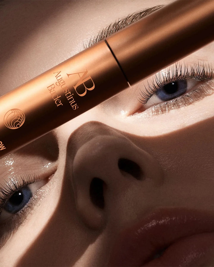 Close-up of a person applying mascara with a brush, focusing on the eye area.