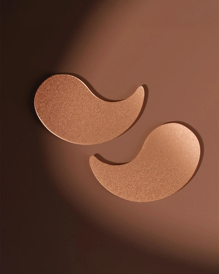 Two bronze-colored eye patches on a brown background