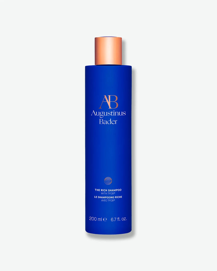 Augustinus Bader The Rich Shampoo in a sleek royal blue 200 mL bottle with a metallic copper-bronze cap, isolated on a clean white background.