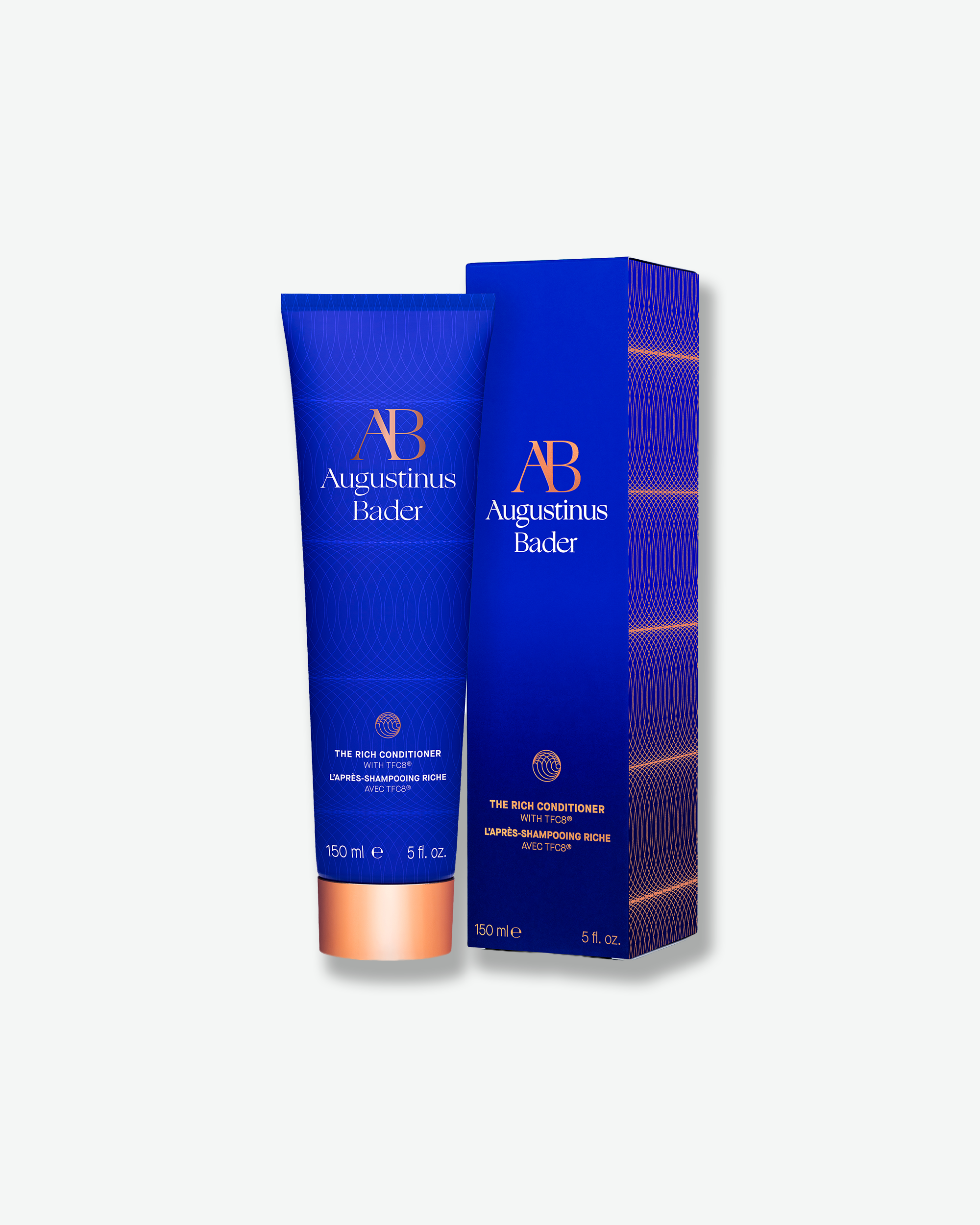 An Augustinus Bader blue conditioner tube standing next to its matching blue outer cardboard packaging box.