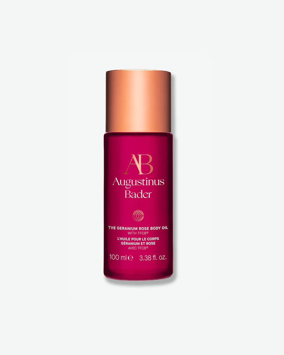 A vertical product shot of Augustinus Bader The Geranium Rose Body Oil in a 100 ml bottle. The container is a vibrant magenta pink with a metallic rose gold cap. The brand’s "AB" monogram and product details are printed on the front in elegant gold lettering.