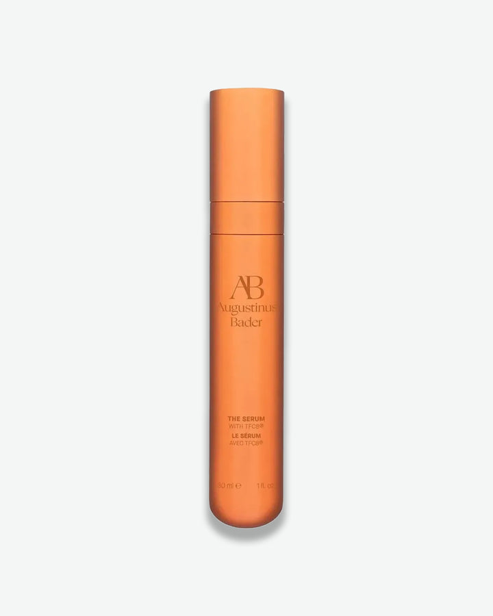 Orange skincare serum bottle with brand name on a light gray background