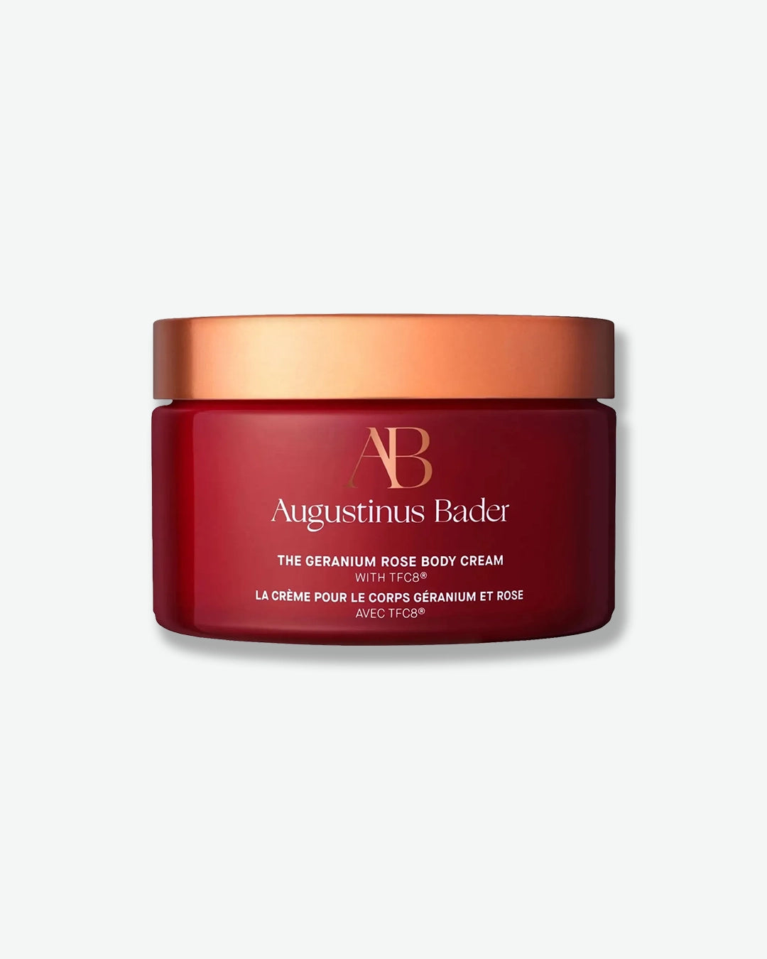 Red jar of Augustinus Bader body cream with a gold lid on a white background