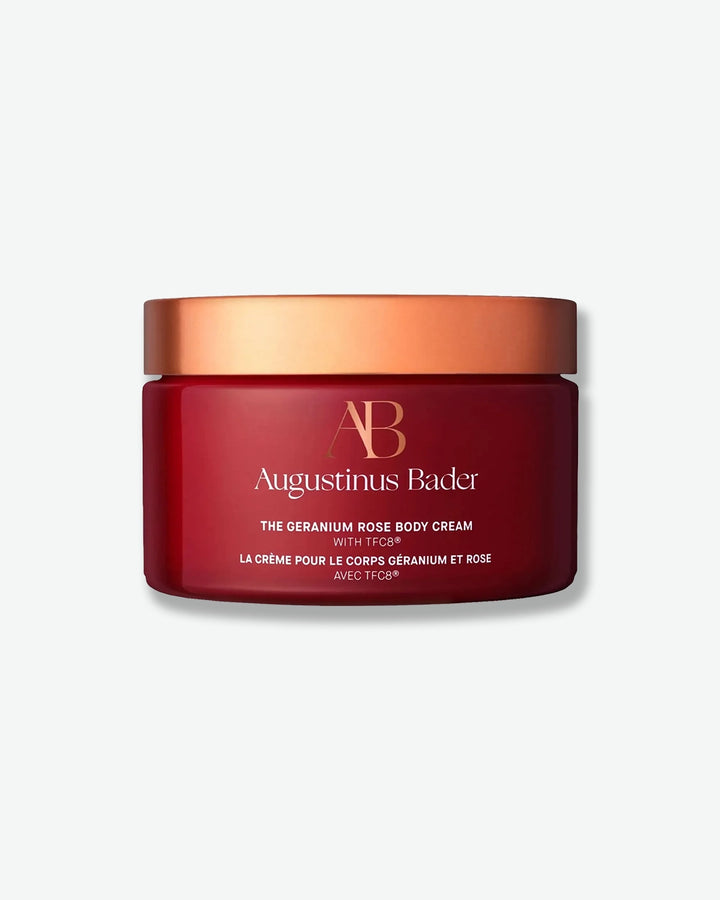 Red jar of Augustinus Bader body cream with a gold lid on a white background