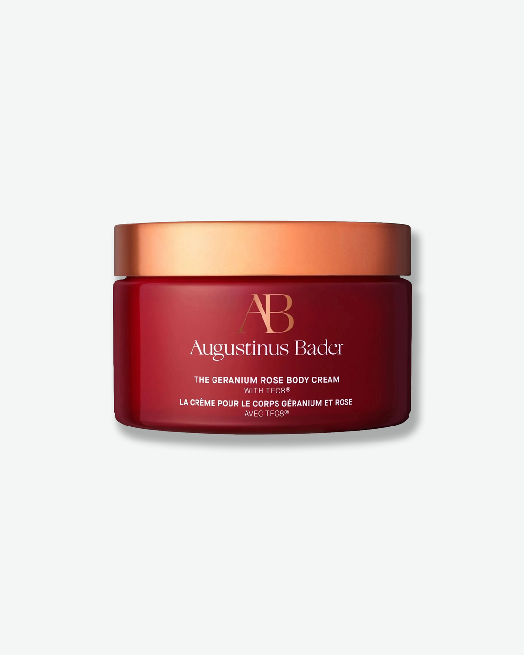 Red jar of Augustinus Bader body cream with a gold lid on a white background