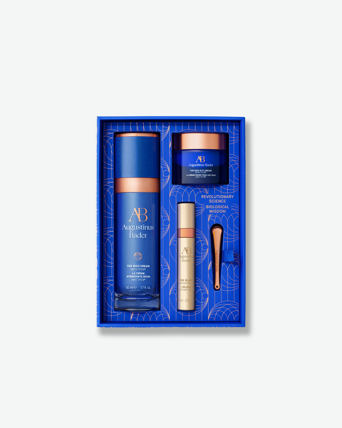 Augustinus Bader The Rich Rejuvenation Trio arranged inside its blue presentation box with skincare products and applicator.