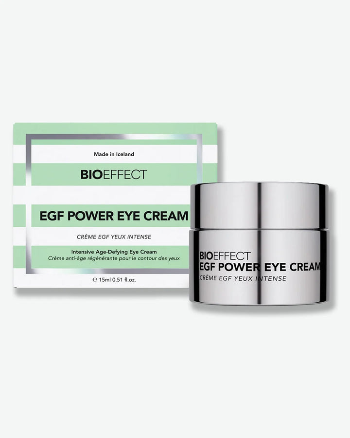 Reflective silver color jar of BIOEFFECT EGF Power Eye Cream stood next to horizontally green and white striped packaging on a white background