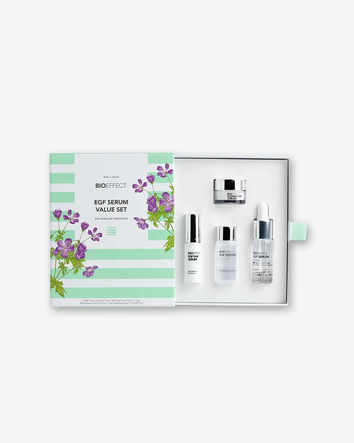The Bioeffect EGF Serum Value Set displayed open against a clean, white background. On the left is the box lid, decorated with light green horizontal stripes and illustrations of purple flowers. On the right, the open box nested with four miniature skincare products: Bioeffect Hydrating Cream, EGF Day Serum, EGF Essence, and the EGF Serum with a white dropper cap.