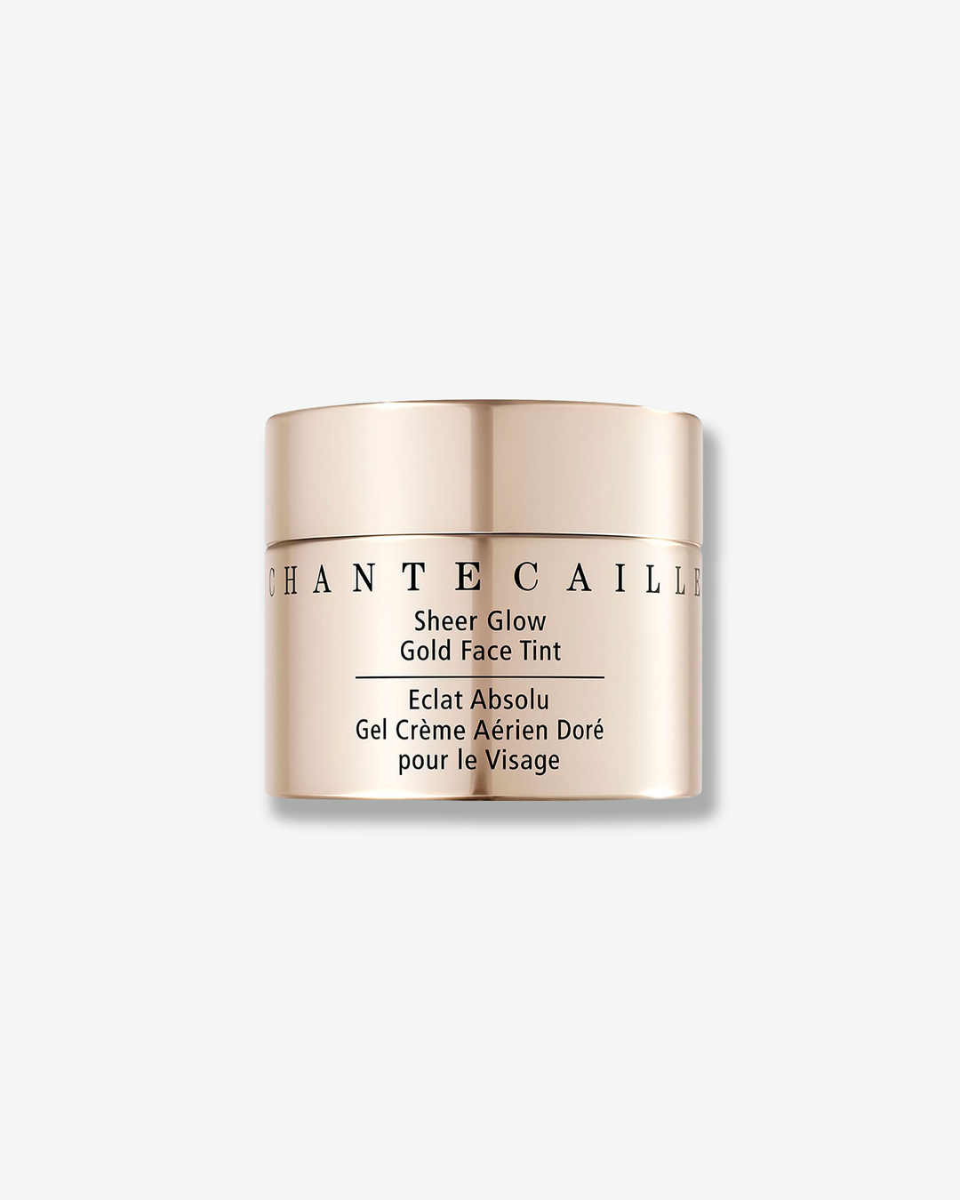 Front view of a Chantecaille Sheer Glow Gold Face Tint jar against a plain gray background. The cylindrical cosmetic container features a reflective, metallic warm champagne gold finish with the brand name and product description printed in black text.