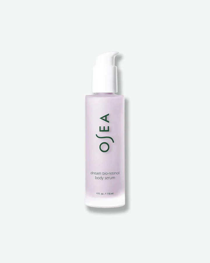 A vertical product shot of OSEA Dream Bio-Retinol Body Serum in a 4 fl. oz. (118 ml) bottle. The milky, pale lavender serum is contained within a tall, slim frosted glass bottle fitted with a white pump cap. The dark green OSEA brand logo and minimalist text are printed vertically down the center of the bottle against a plain white background.
