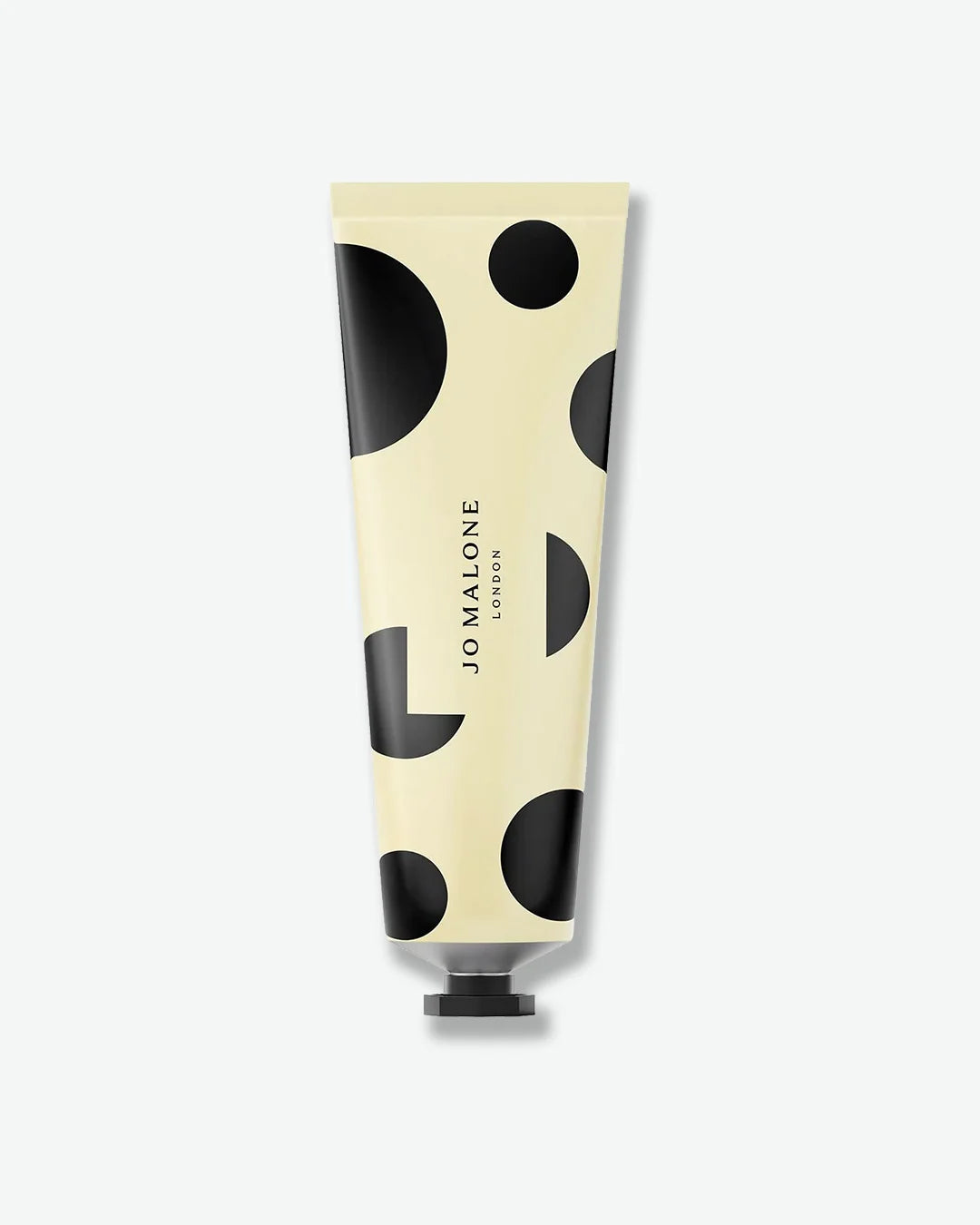 Hand cream tube with black polka dot design on a white background