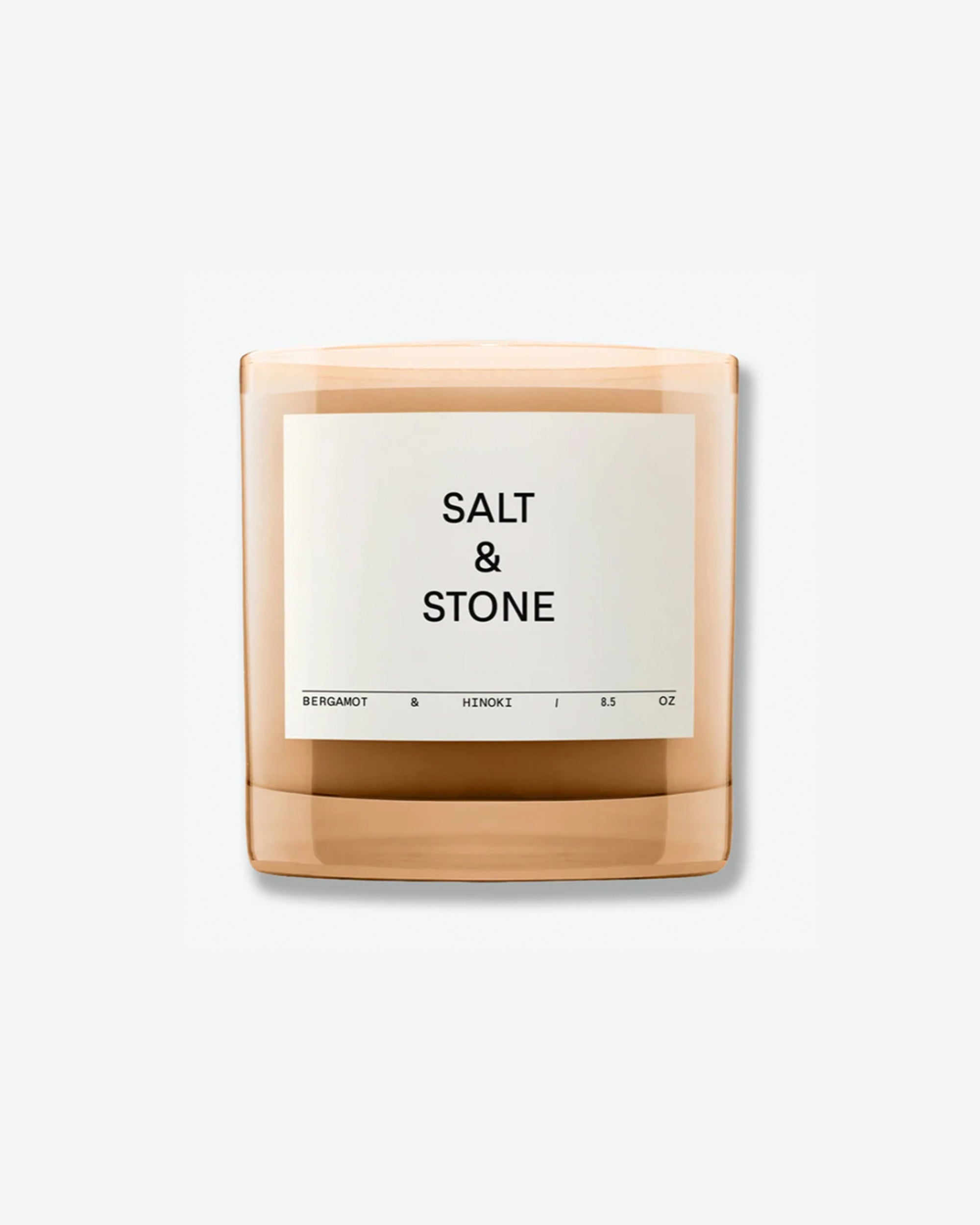 Salt & Stone Bergamot & Hinoki 8.5 oz scented candle in a minimalist translucent amber glass jar with a square off-white label, isolated against a light grey background.