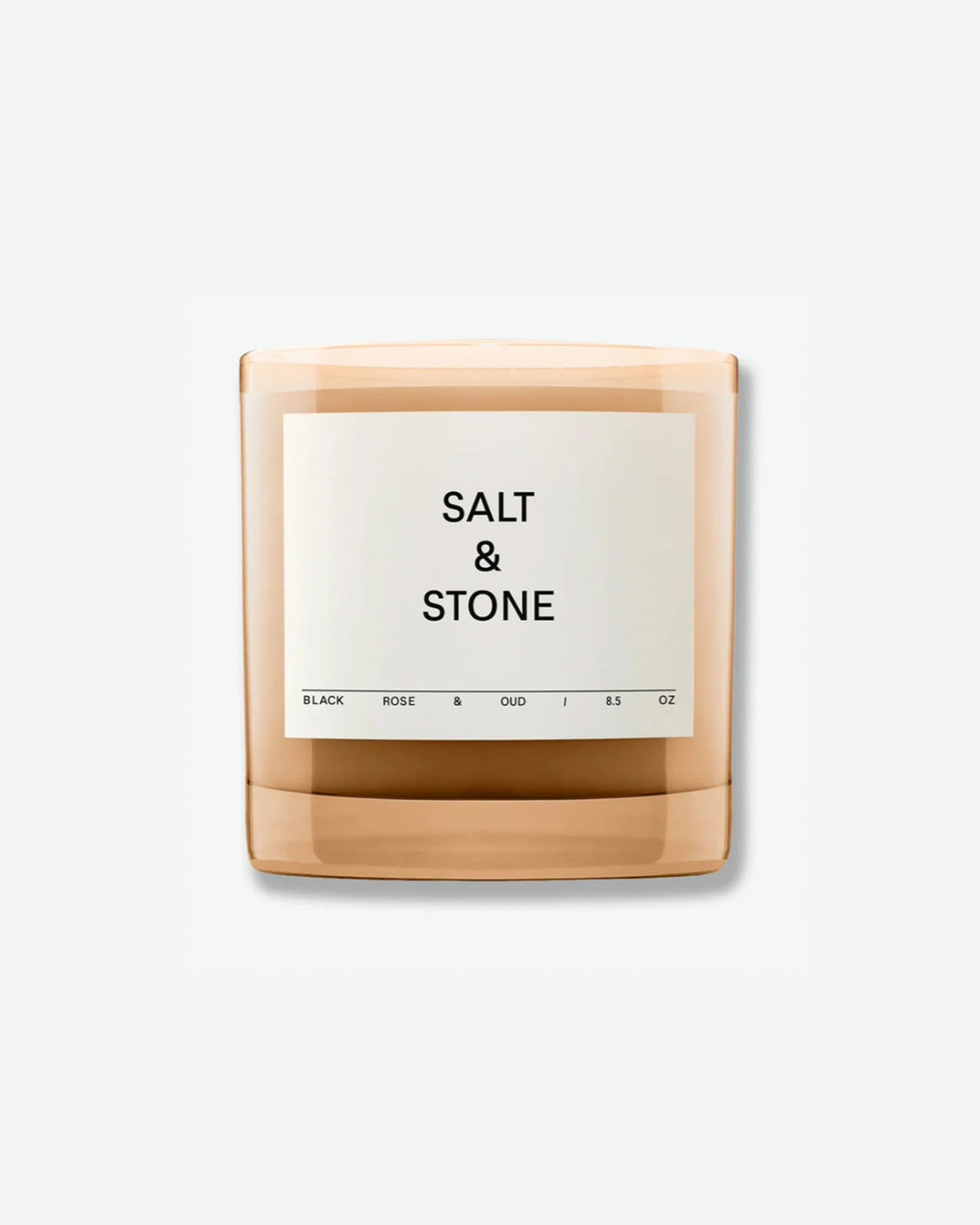 Salt & Stone Black Rose & Oud 8.5 oz scented candle in a minimalist translucent amber glass jar with a square off-white label, isolated against a light grey background.