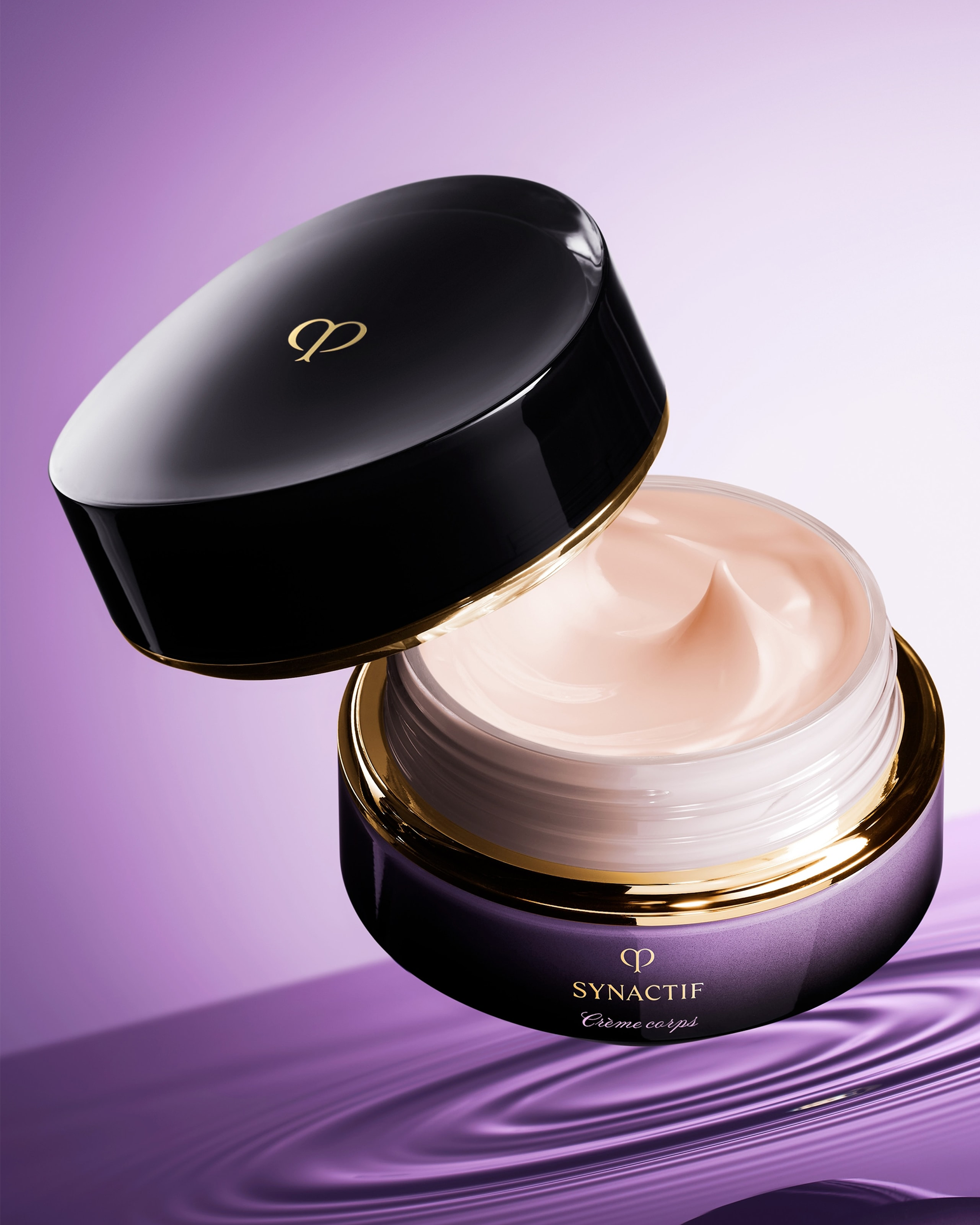 A cosmetic cream jar with its lid off, showing a smooth pale beige cream inside. The jar is dark purple with gold trim and the brand name SYNACTIF visible.