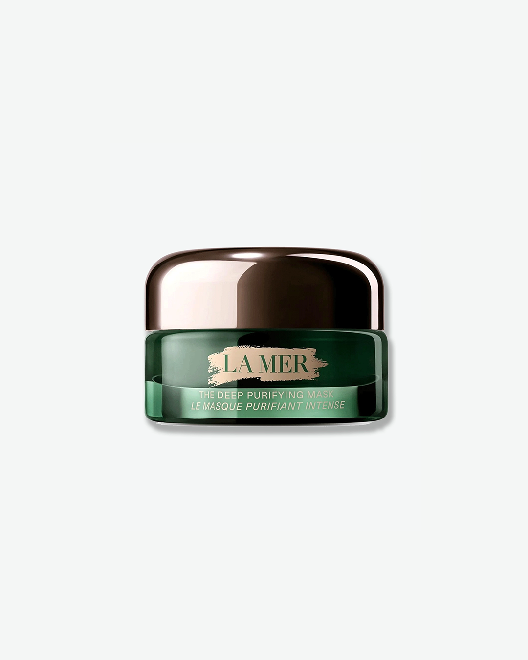 A product shot of a La Mer The Deep Purifying Mask jar, centered against a plain light gray background. The low, wide-mouthed glass jar has a rich emerald-green tint, paired with a polished gunmetal-silver dome cap. The front features the signature pale pink paint-stroke design with the "LA MER" branding, above pale green typography reading "THE DEEP PURIFYING MASK / LE MASQUE PURIFIANT INTENSE".