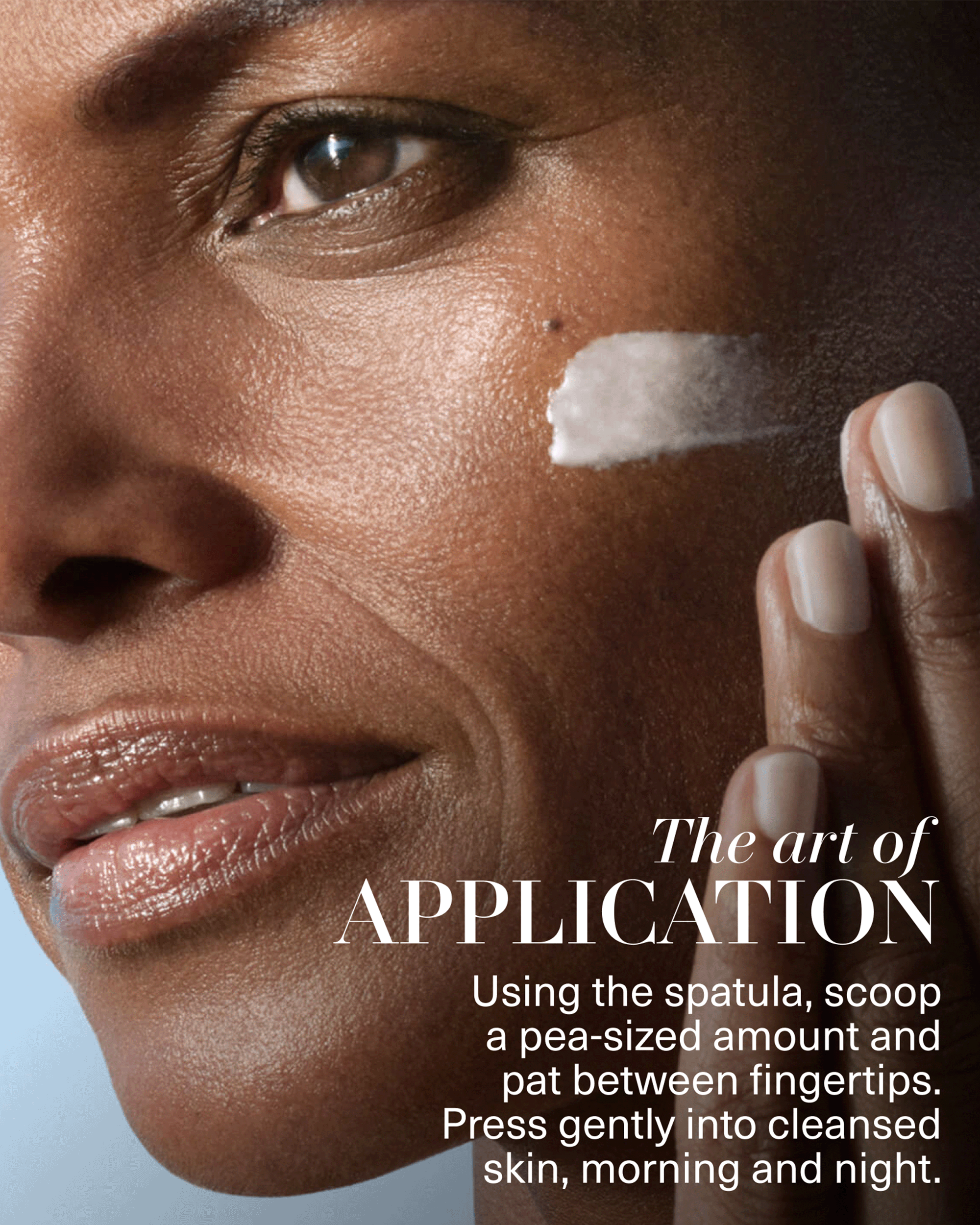 Close-up of a model applying The Moisturizing Soft Cream to her cheek, with directions to scoop a pea-sized amount, pat between fingertips, and press into cleansed skin morning and night.
