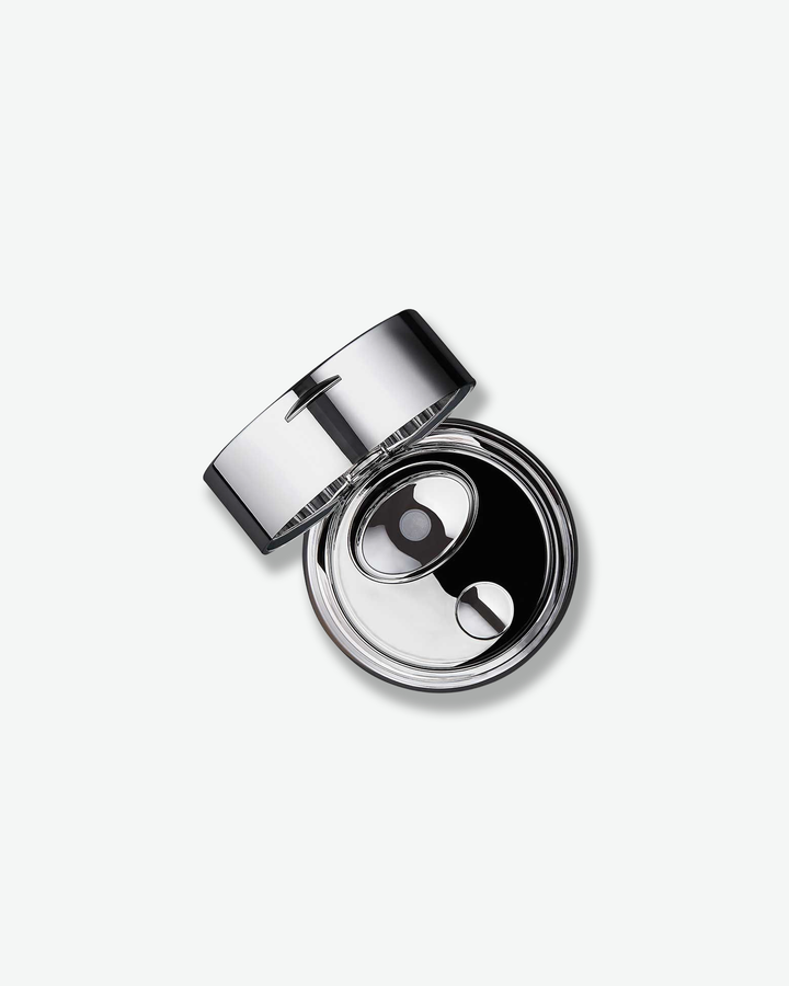 An overhead, top-down view looking into the open La Prairie Skin Caviar Absolute Filler container. The polished silver lid is angled back, revealing a sleek, mirror-like chrome interior surface with a stylized oval button mechanism designed to cleanly dispense the product.