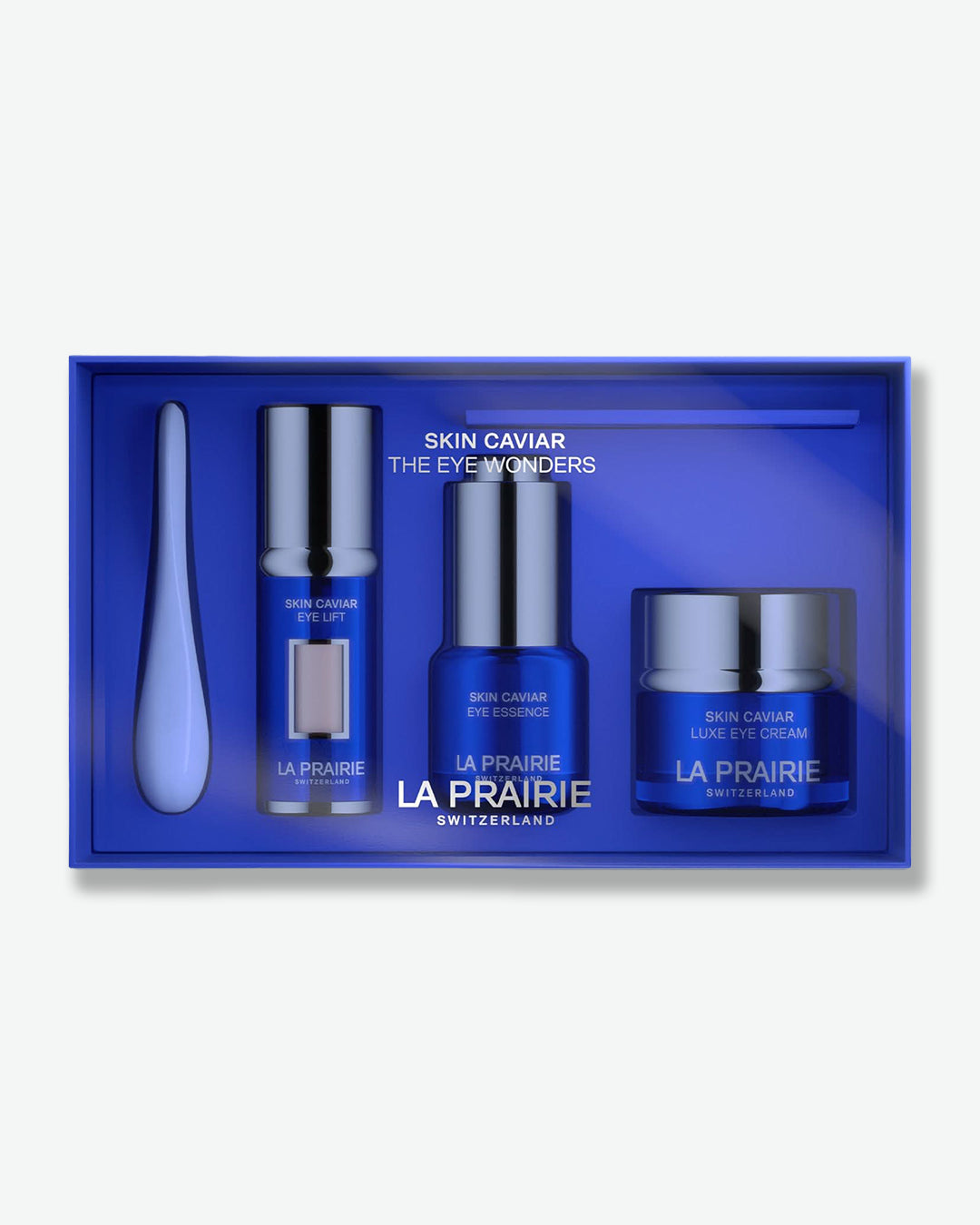 A close-up view of the open La Prairie Skin Caviar The Eye Wonders gift box, neatly holding a silver applicator tool, Eye Lift serum, Eye Essence, and Luxe Eye Cream.