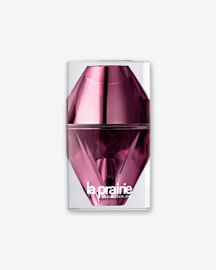 La Prairie Switzerland skincare product encased in a futuristic, diamond-faceted metallic pink and magenta structural bottle inside a clear cylindrical outer shell, isolated on a light grey background.