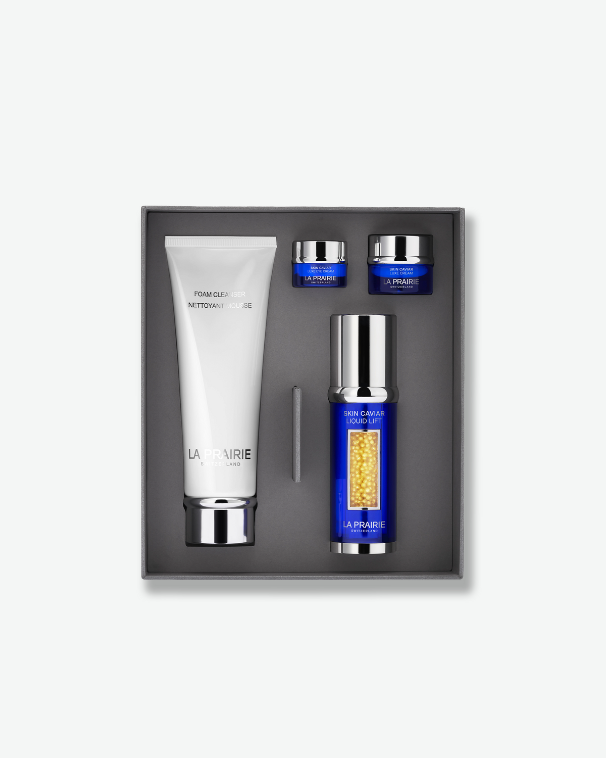 A La Prairie skincare gift set in a gray presentation box, featuring a white cleanser tube alongside cobalt blue jars and bottles of Skin Caviar products.