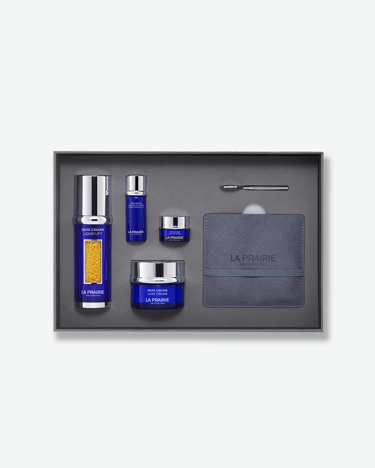La Prairie Skin Caviar lifting and firming skincare set presented in an open grey gift box, featuring Skin Caviar Liquid Lift, Essence-in-Lotion, Luxe Eye Cream, Luxe Cream and a sculpting facial tool.