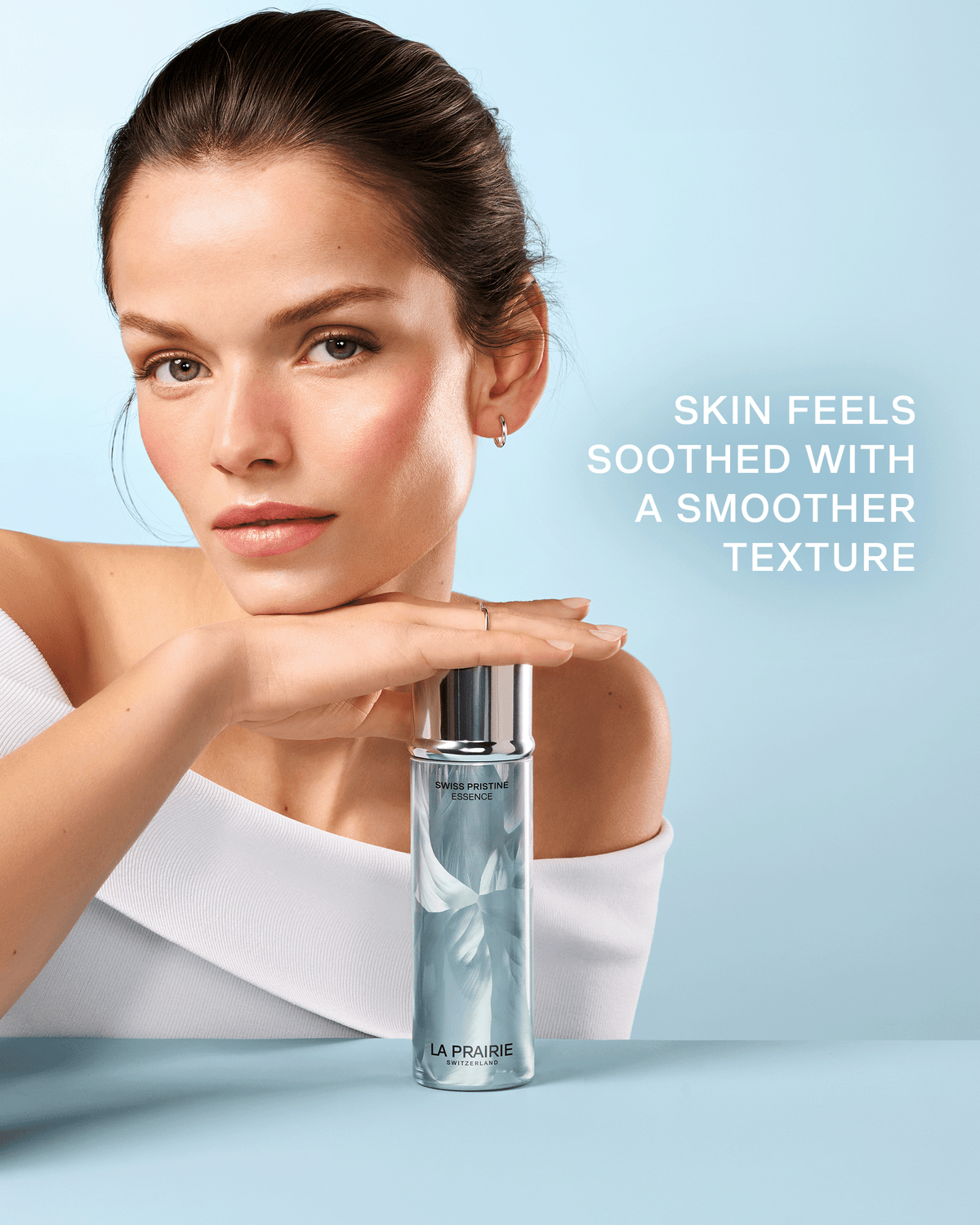 Model posed with Swiss Pristine Essence with text highlighting soothed skin and a smoother-looking texture.