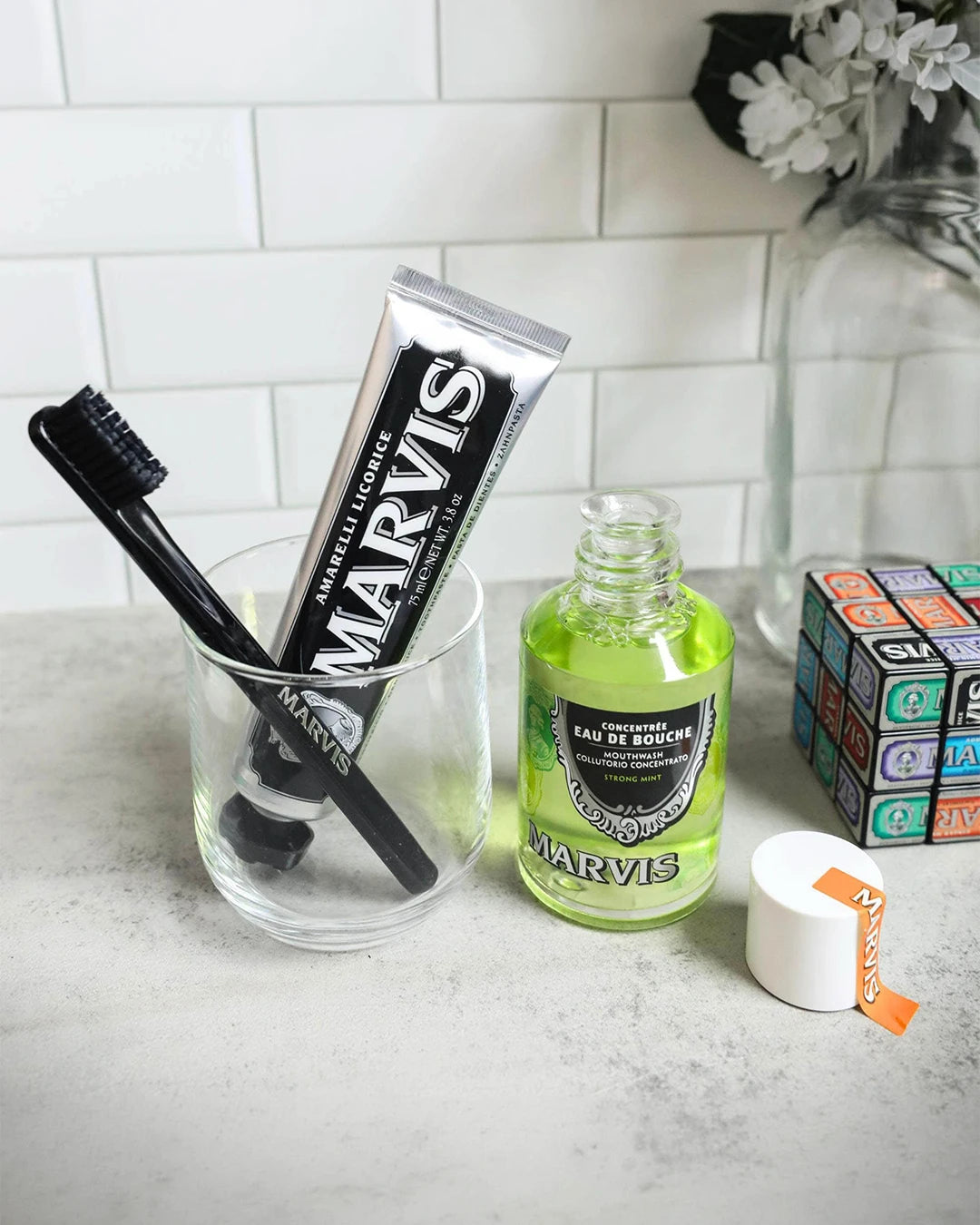 Marvis toothpaste and mouthwash on a bathroom counter with a toothbrush and small container.