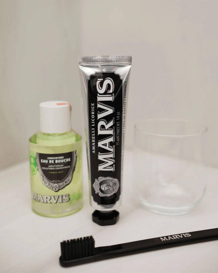 Marvis mouthwash, toothpaste, and toothbrush on a white surface