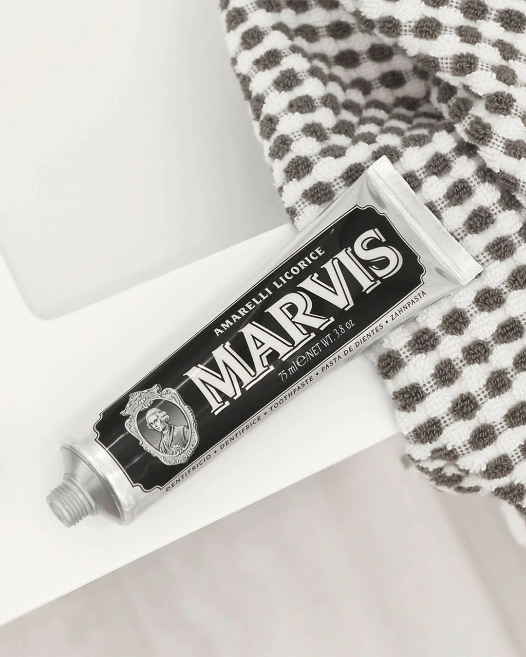 Marvis toothpaste tube on a white surface with a checkered towel